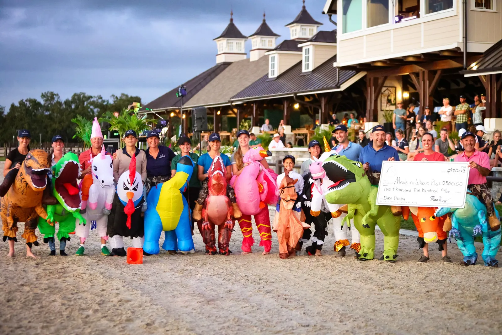Riders in inflatable dinosaur and animal costumes presenting a charity check in front of the pavilion at TerraNova Equestrian Center. Photo by EQ Media.