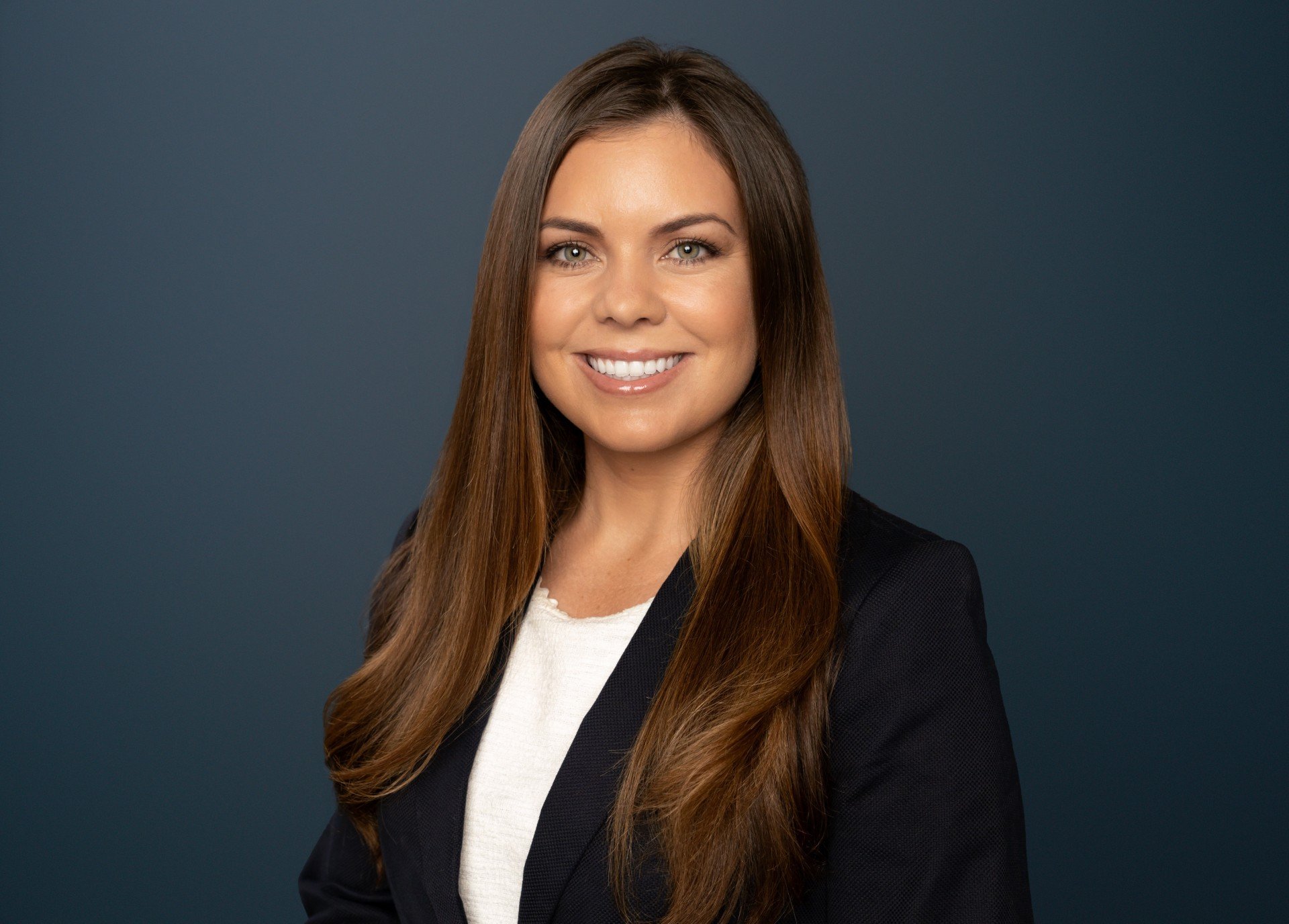 Laura Bostwick, Chief Revenue Officer of TerraNova Equestrian Center, headshot in a navy blazer against a dark blue background