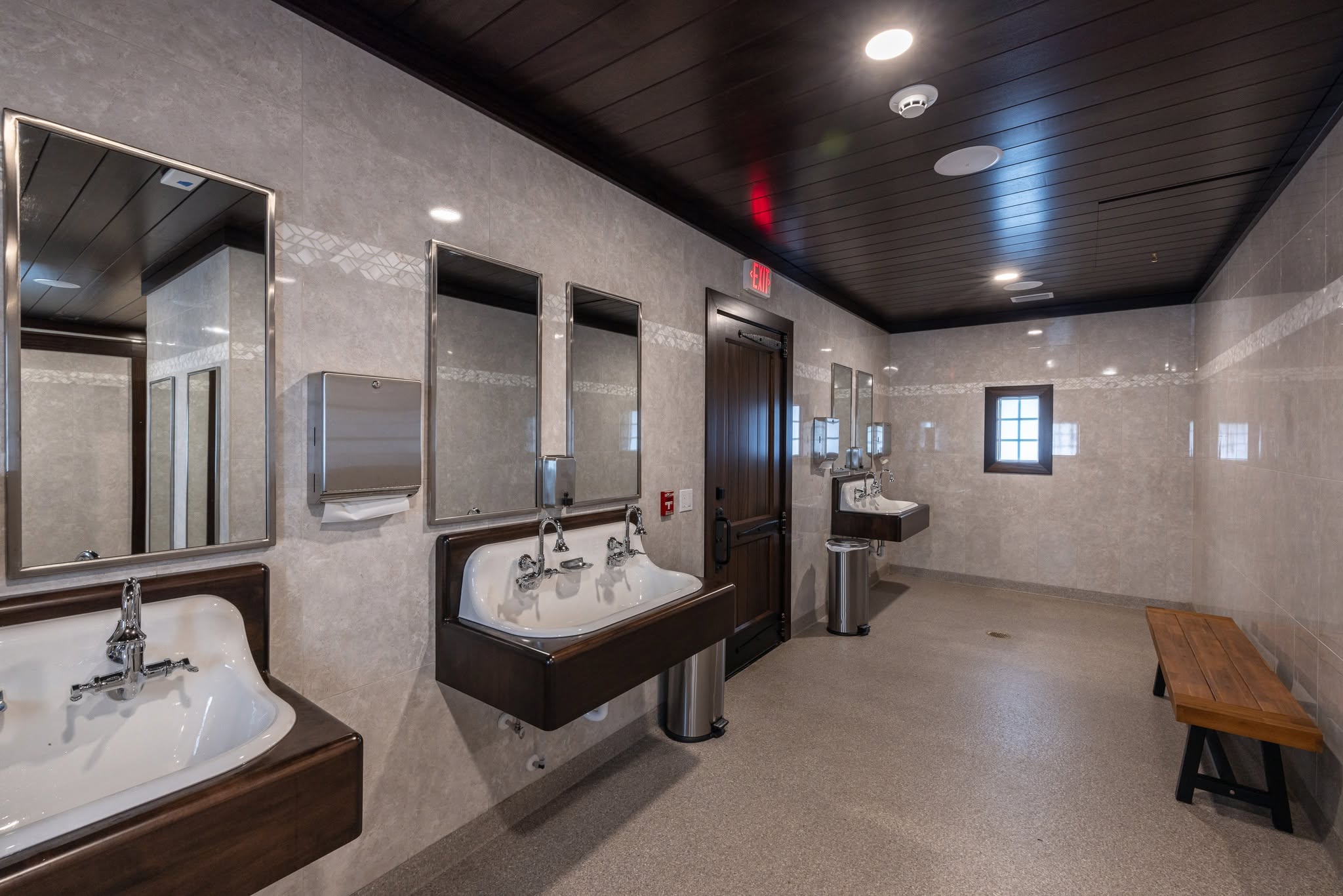 Restroom facility with wood sink counters, mirrors, and a bench at TerraNova Equestrian Center