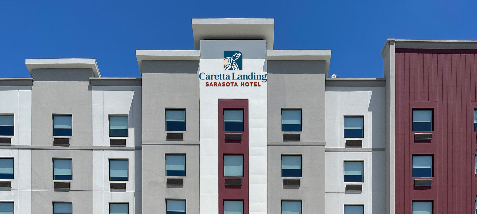 Grey and red hotel facade with the Caretta Landing Sarasota Hotel sign at the top